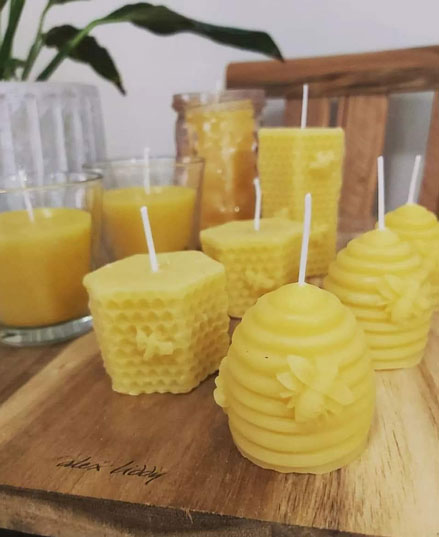 Natural beeswax candles display featuring beehive shapes and decorative bees in outdoor setting